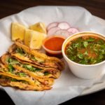 Tacos al pastor, a popular Mexican dish featuring marinated pork cooked on a vertical rotisserie and served with pineapple, cilantro, and onions in a soft corn tortilla.